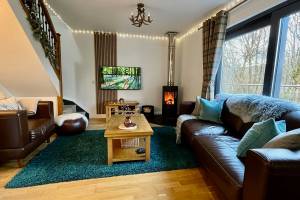 The cosy lounge with wood-burning stive and glass picture windows at Bluebell Cottage Glencoe.